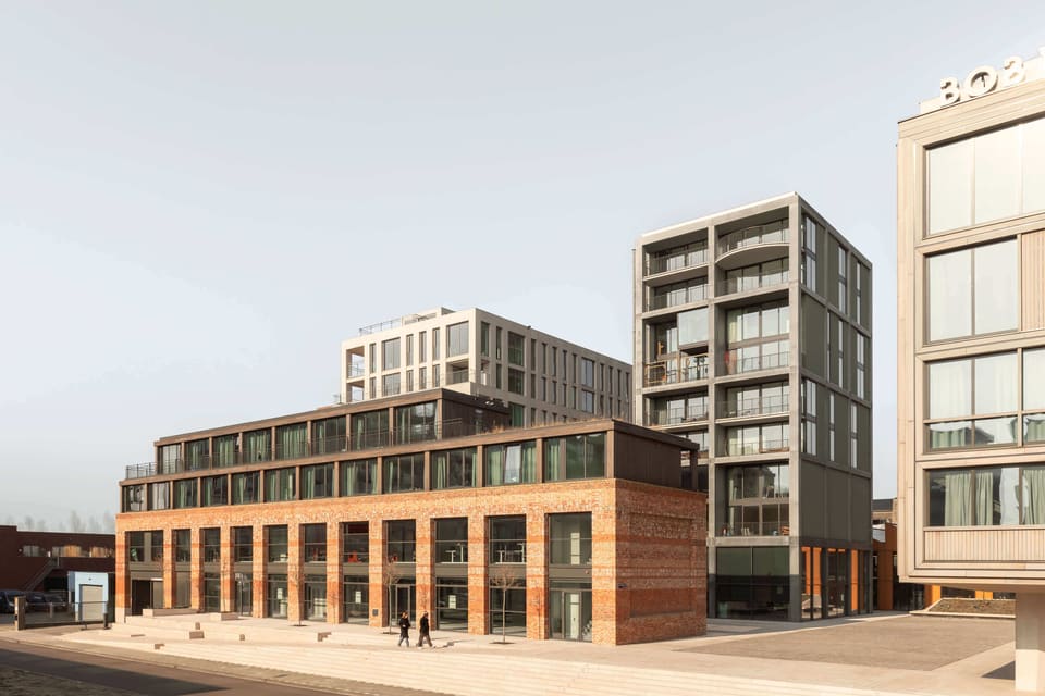 Republica from the street: low recycled-brick buildings in front of the residential towers