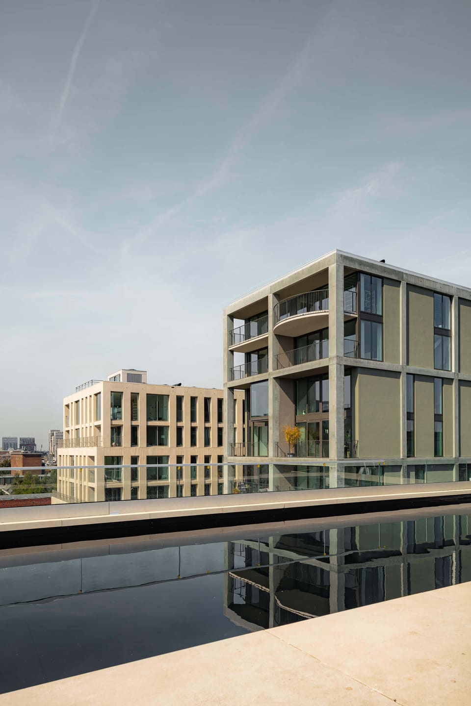 The rooftop pool reflecting the white block and the green tower