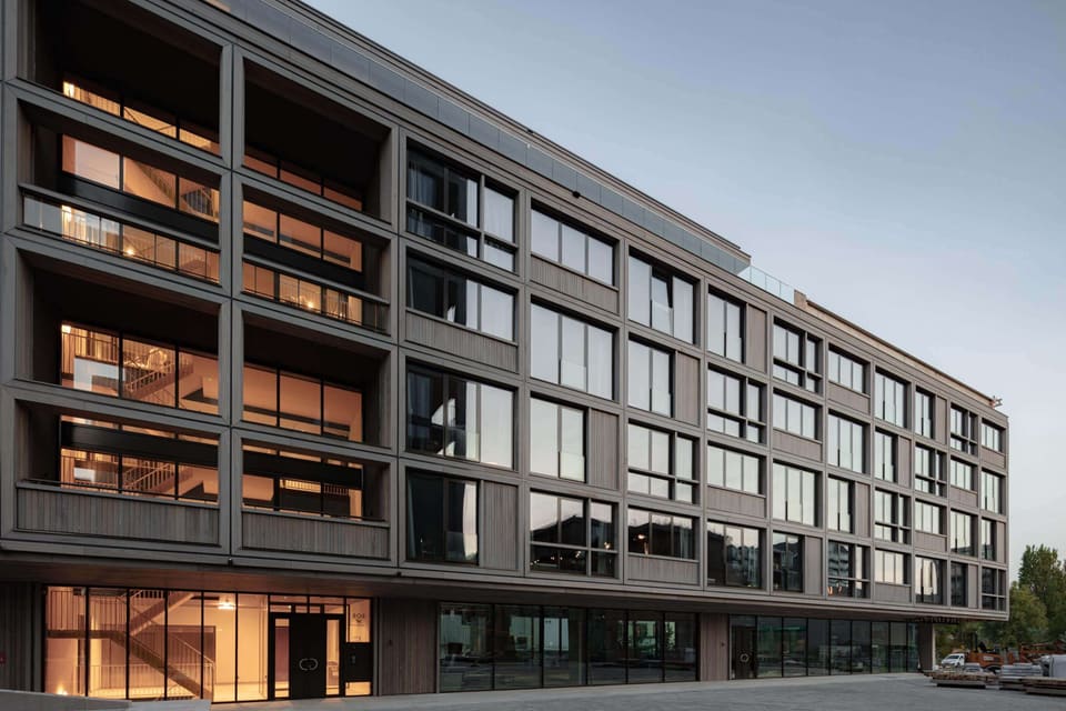 The long residential facade at dusk with lit windows