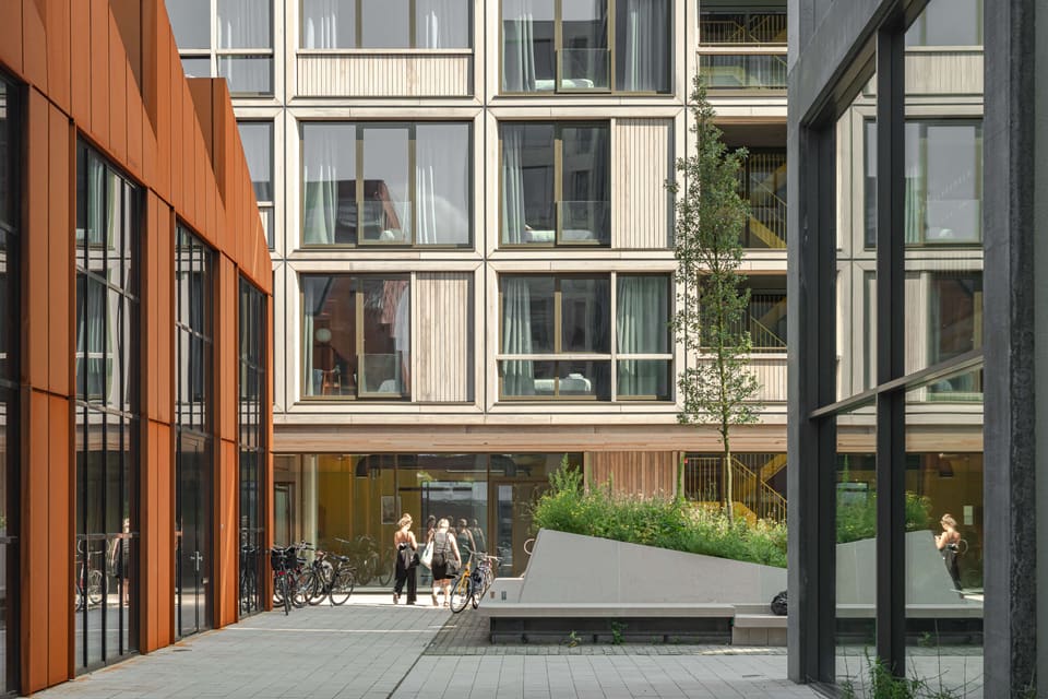 The green courtyard between brick and timber facades
