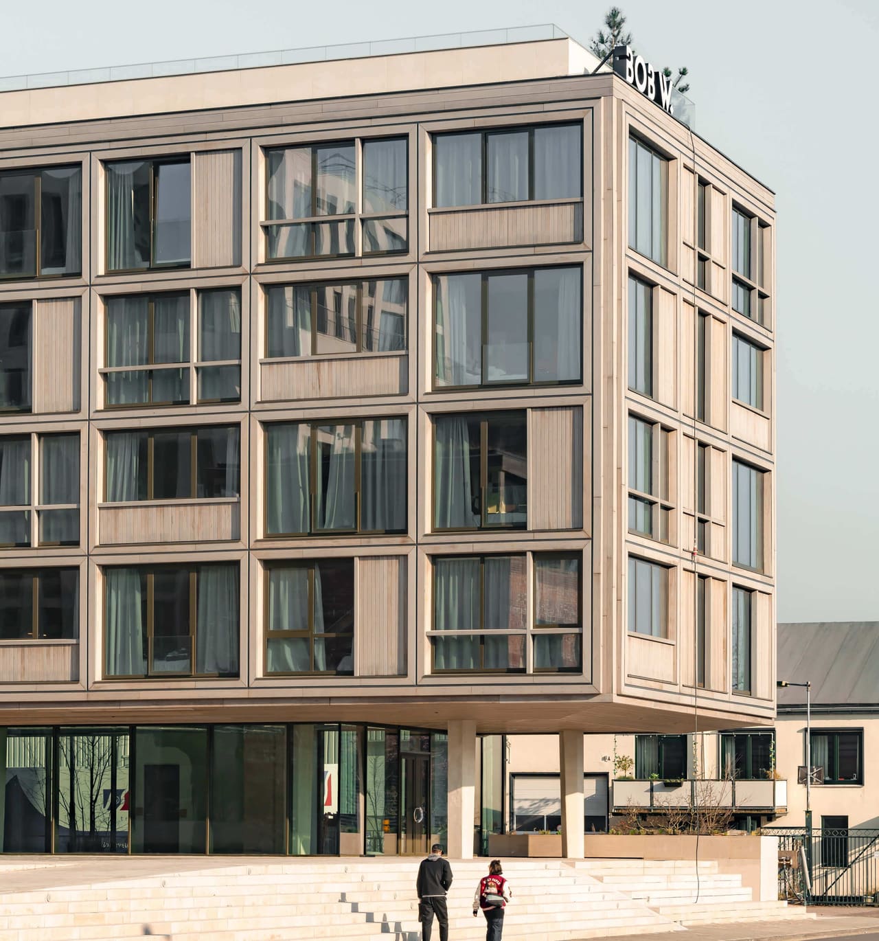 Frontal view of the timber-clad apartment-hotel at Republica, a regular grid of storey-high frames above a glazed plinth